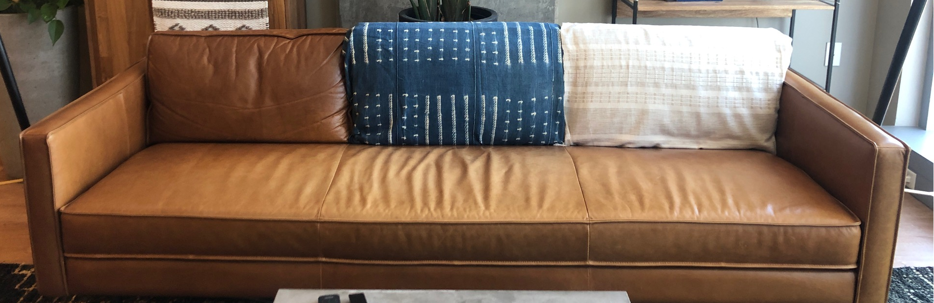 Leather couch with decorative blanket draped over cushion